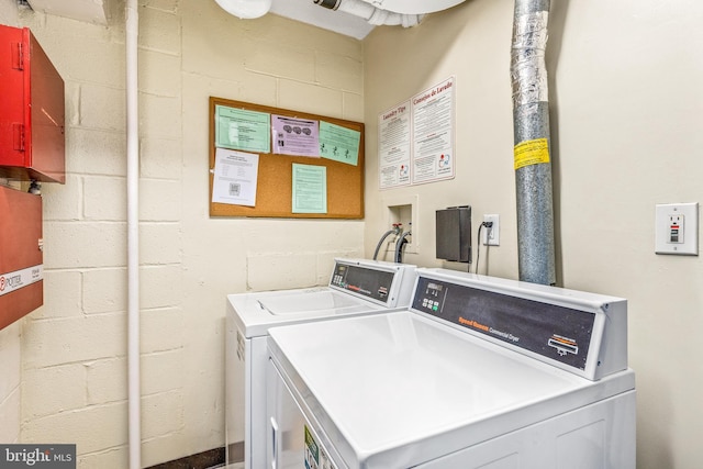 community laundry room with washing machine and dryer and concrete block wall