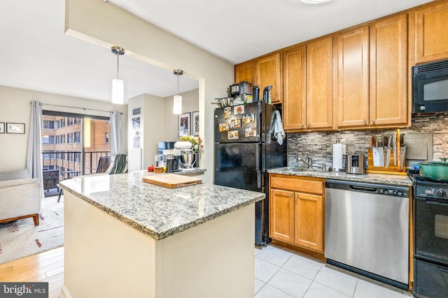 kitchen with light stone counters, brown cabinets, decorative backsplash, a kitchen island, and black appliances