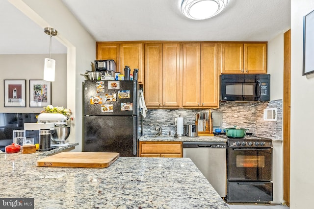 kitchen featuring light stone countertops, hanging light fixtures, backsplash, brown cabinets, and black appliances