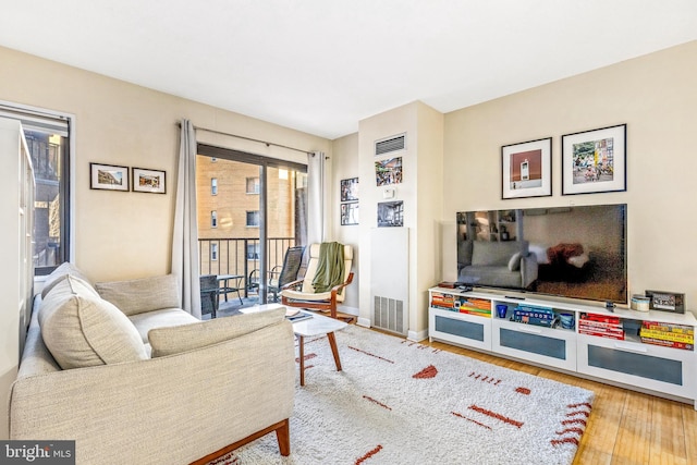 living area featuring visible vents, baseboards, and wood finished floors