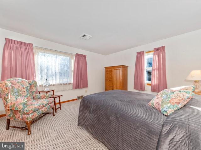 bedroom with baseboards, visible vents, and light colored carpet