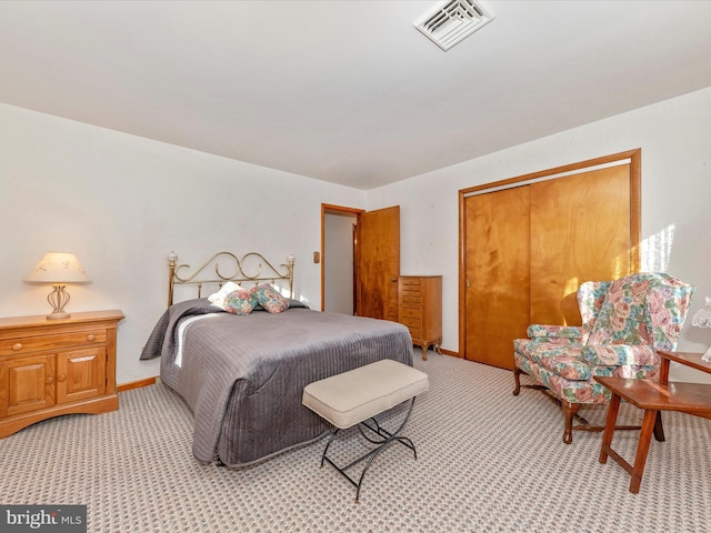 bedroom with a closet, visible vents, light carpet, and baseboards