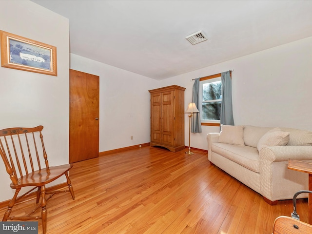 living area featuring light wood-style flooring, visible vents, and baseboards