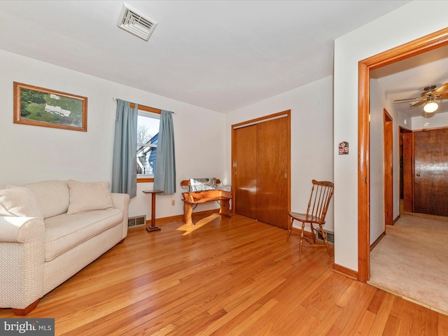 sitting room with light wood-style flooring, visible vents, and baseboards