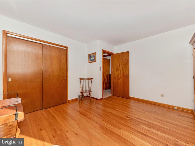 unfurnished bedroom with light wood-type flooring, baseboards, and a closet