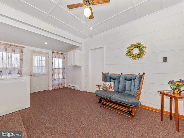 living area with a ceiling fan, a baseboard heating unit, coffered ceiling, and carpet flooring