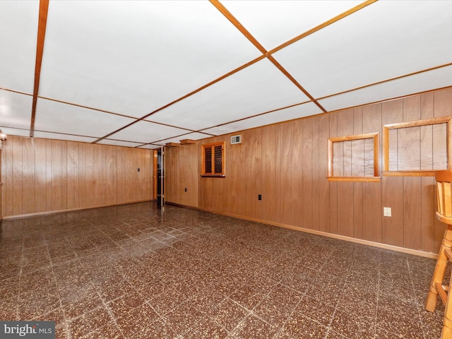 finished basement featuring wood walls, visible vents, and tile patterned floors