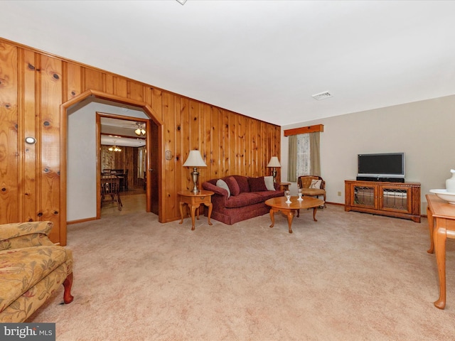 living room with wood walls, visible vents, and light colored carpet