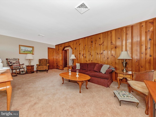 carpeted living room featuring visible vents and wooden walls