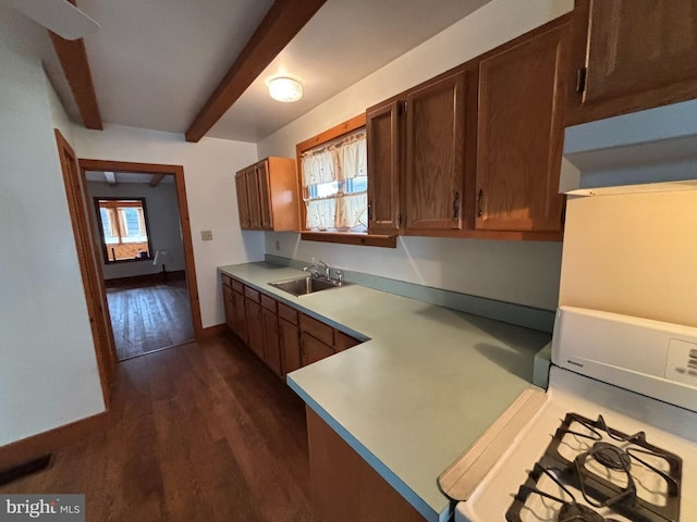 kitchen featuring dark wood-style flooring, gas range gas stove, light countertops, a sink, and beamed ceiling