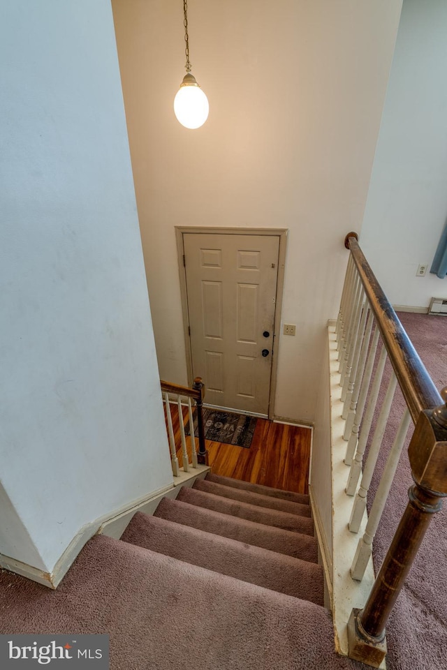 staircase with carpet floors and a towering ceiling