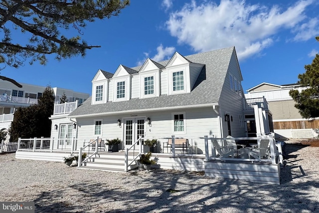 cape cod house featuring french doors, roof with shingles, and a deck