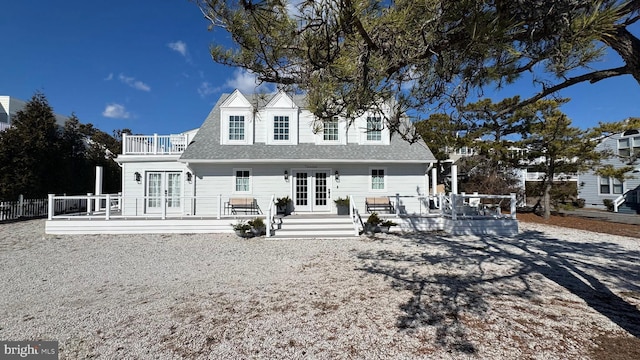 back of property with french doors, roof with shingles, fence, and a wooden deck