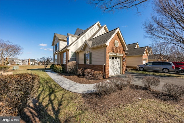 view of side of property with a yard, brick siding, an attached garage, and aphalt driveway