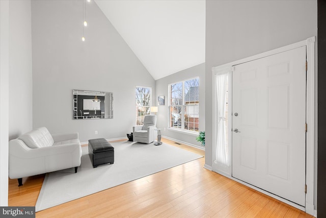 foyer entrance with high vaulted ceiling, visible vents, baseboards, and wood finished floors