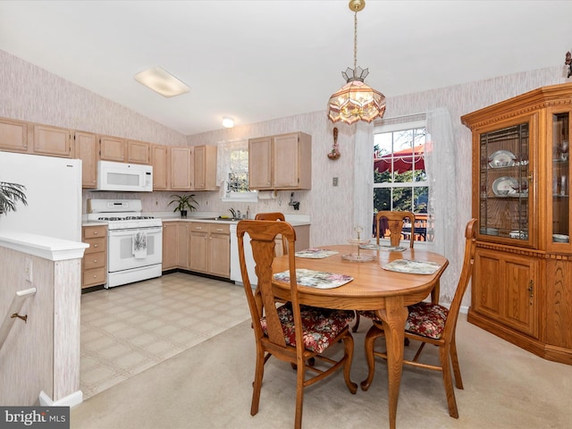 dining area featuring wallpapered walls, vaulted ceiling, and light floors