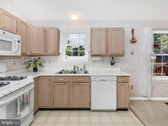 kitchen with white appliances, wallpapered walls, light countertops, and a sink