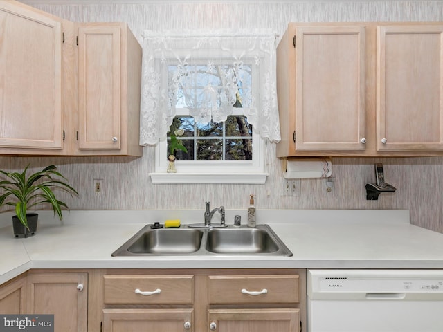 kitchen featuring light countertops, white dishwasher, a sink, and light brown cabinetry