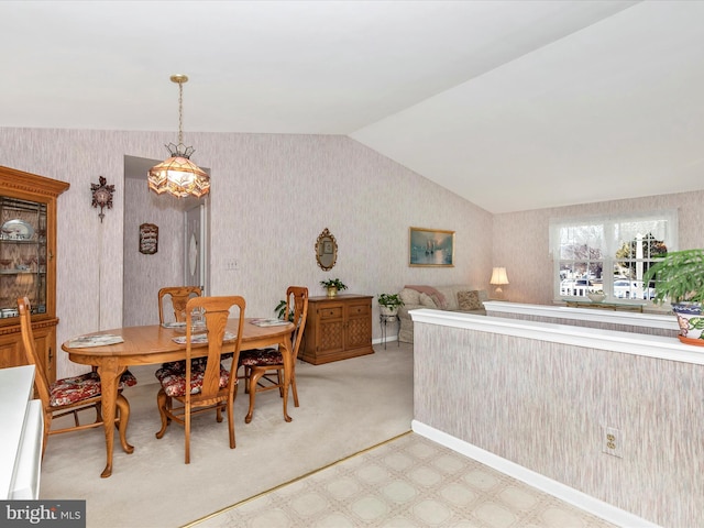 dining area featuring vaulted ceiling and wallpapered walls