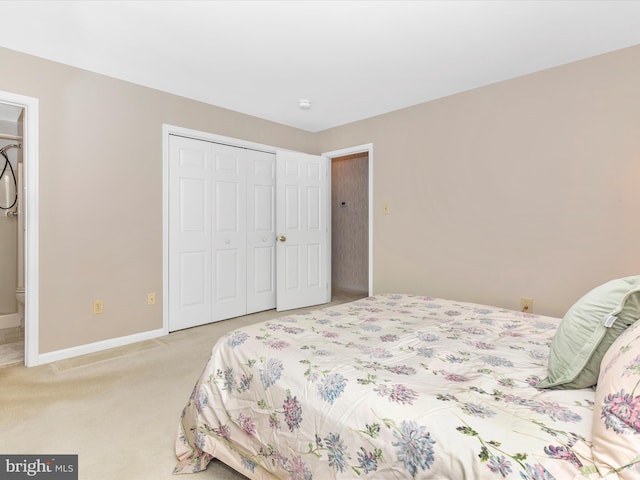 bedroom with baseboards, a closet, ensuite bathroom, and light colored carpet