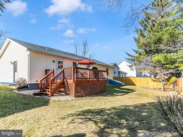 rear view of house featuring fence, a deck, and a lawn