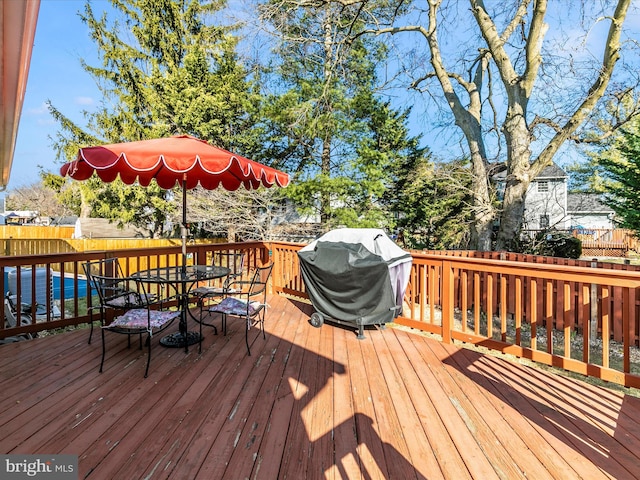 wooden terrace with outdoor dining area, area for grilling, and fence