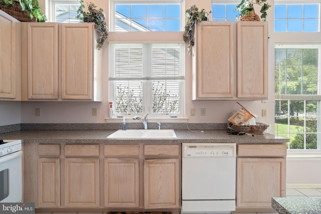 kitchen featuring light brown cabinets, white appliances, and a sink