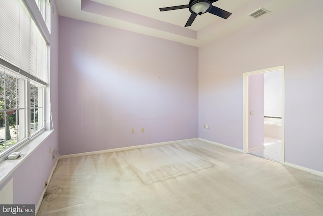 spare room featuring baseboards, visible vents, a ceiling fan, and light colored carpet