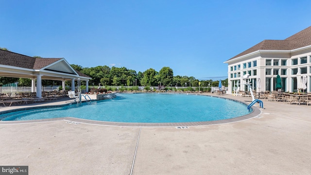 community pool with a patio area and fence