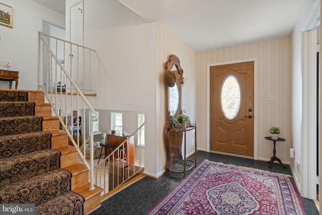 foyer featuring stairs, baseboards, and wallpapered walls