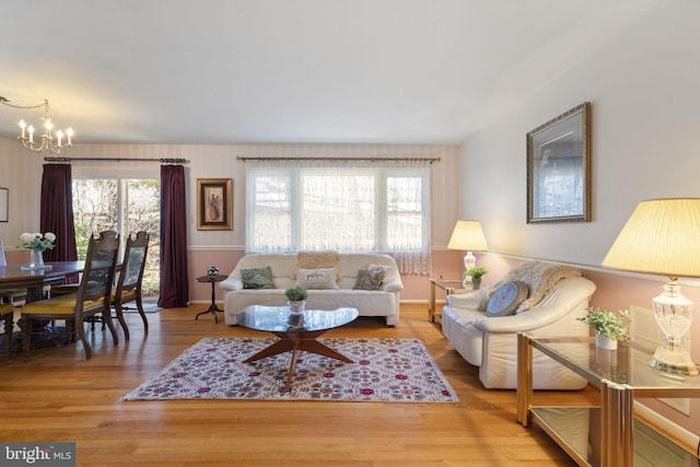 living room featuring a notable chandelier, wood finished floors, and a healthy amount of sunlight