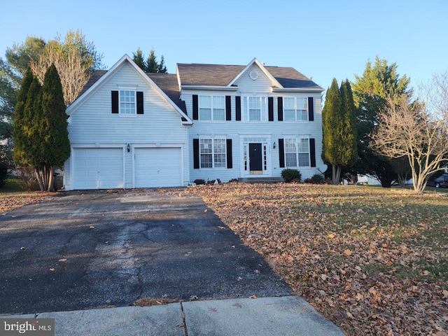 colonial inspired home featuring an attached garage and aphalt driveway