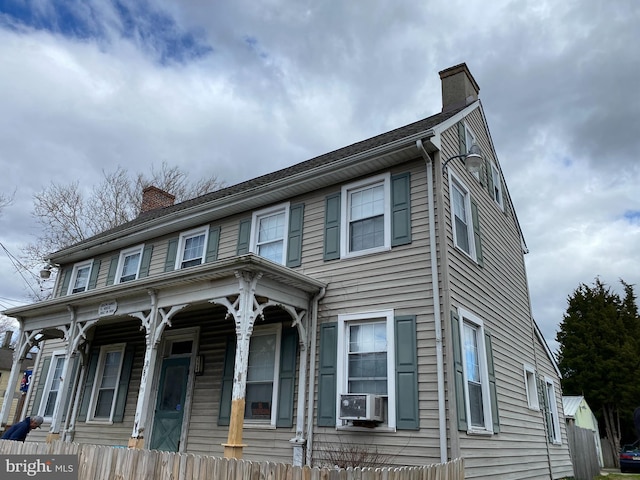 view of front of home with a porch, fence, and a chimney