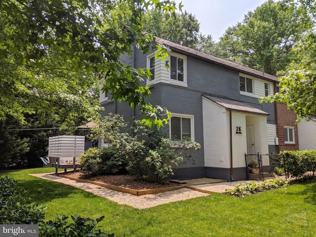 view of front of house featuring brick siding, fence, and a front lawn