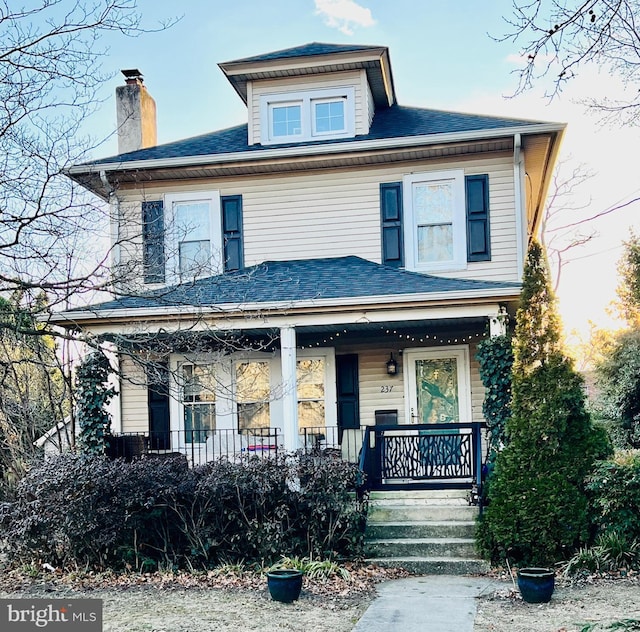 american foursquare style home featuring a shingled roof and covered porch