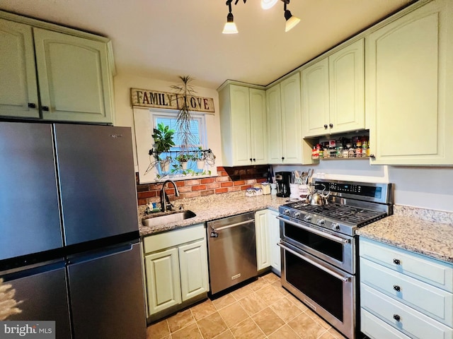 kitchen featuring pendant lighting, stainless steel appliances, a sink, and light stone countertops