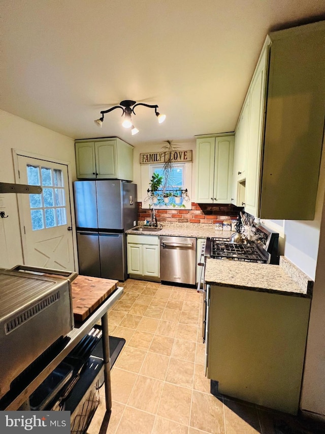 kitchen with stainless steel appliances, tasteful backsplash, light countertops, green cabinets, and a sink