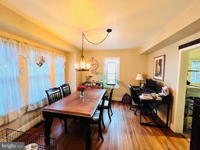 dining space featuring a notable chandelier, plenty of natural light, wood finished floors, and baseboards