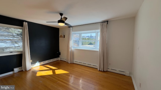 unfurnished bedroom featuring ceiling fan, baseboard heating, light wood-type flooring, and baseboards