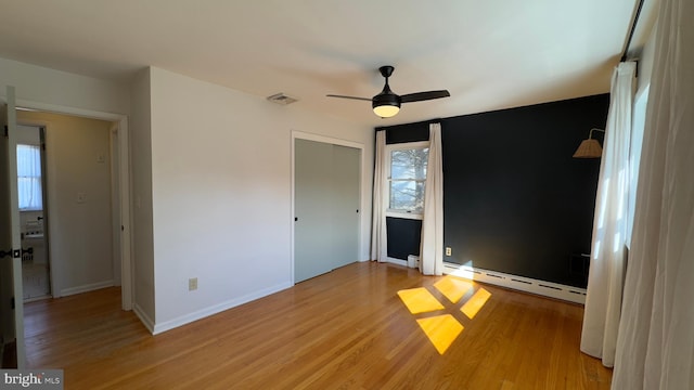 unfurnished bedroom with baseboards, visible vents, ceiling fan, baseboard heating, and light wood-style floors