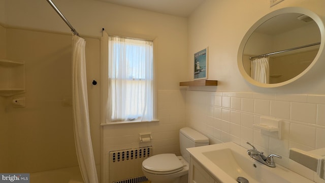 full bath featuring toilet, a wainscoted wall, radiator heating unit, curtained shower, and tile walls