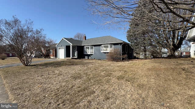 view of front of property featuring a garage, driveway, a chimney, and a front yard