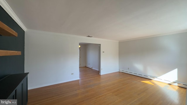 spare room featuring visible vents, baseboard heating, light wood-style floors, ornamental molding, and baseboards