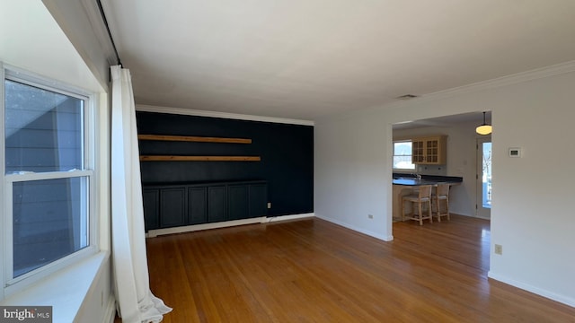 unfurnished room featuring baseboards, visible vents, ornamental molding, and wood finished floors