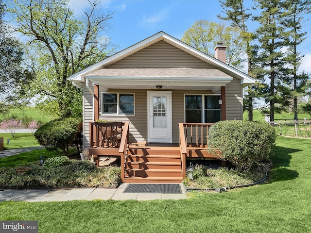 bungalow featuring a chimney, roof with shingles, a front yard, and covered porch