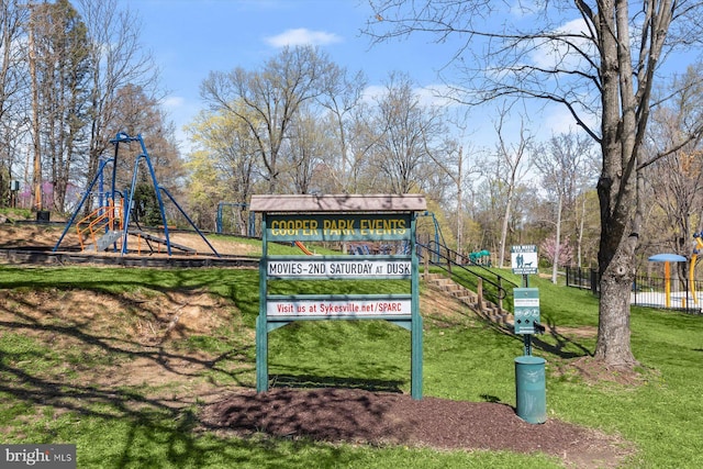 view of property's community featuring playground community, a lawn, and fence