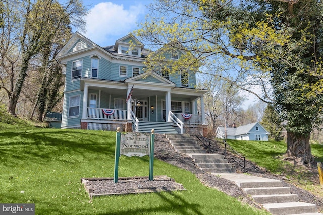 victorian-style house with stairway, a front yard, and covered porch