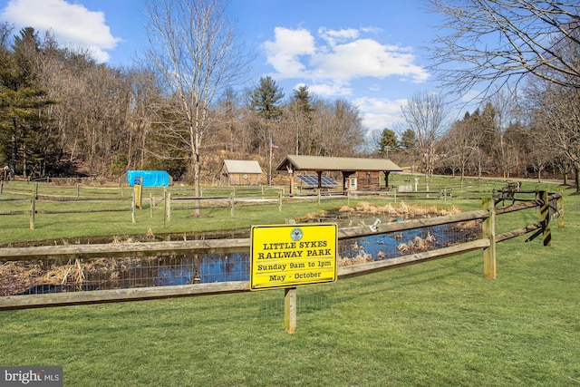view of property's community with a lawn and fence