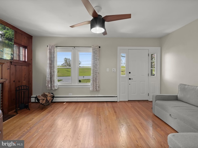 entrance foyer featuring a baseboard heating unit, wood finished floors, a wealth of natural light, and ceiling fan