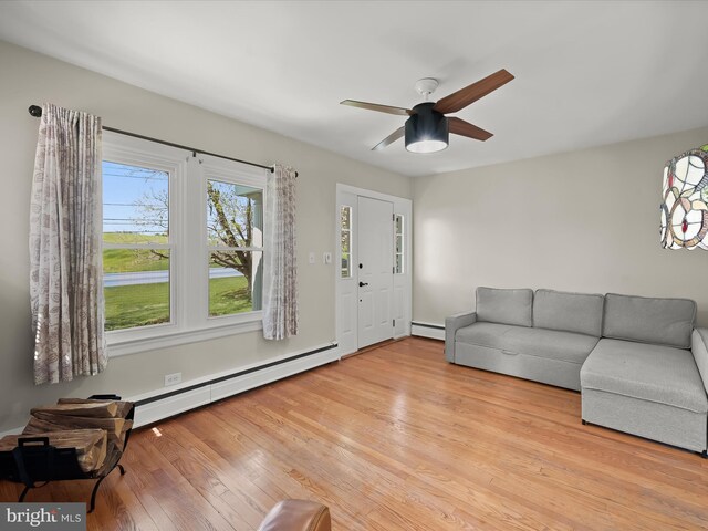 living area featuring baseboard heating, wood finished floors, and ceiling fan